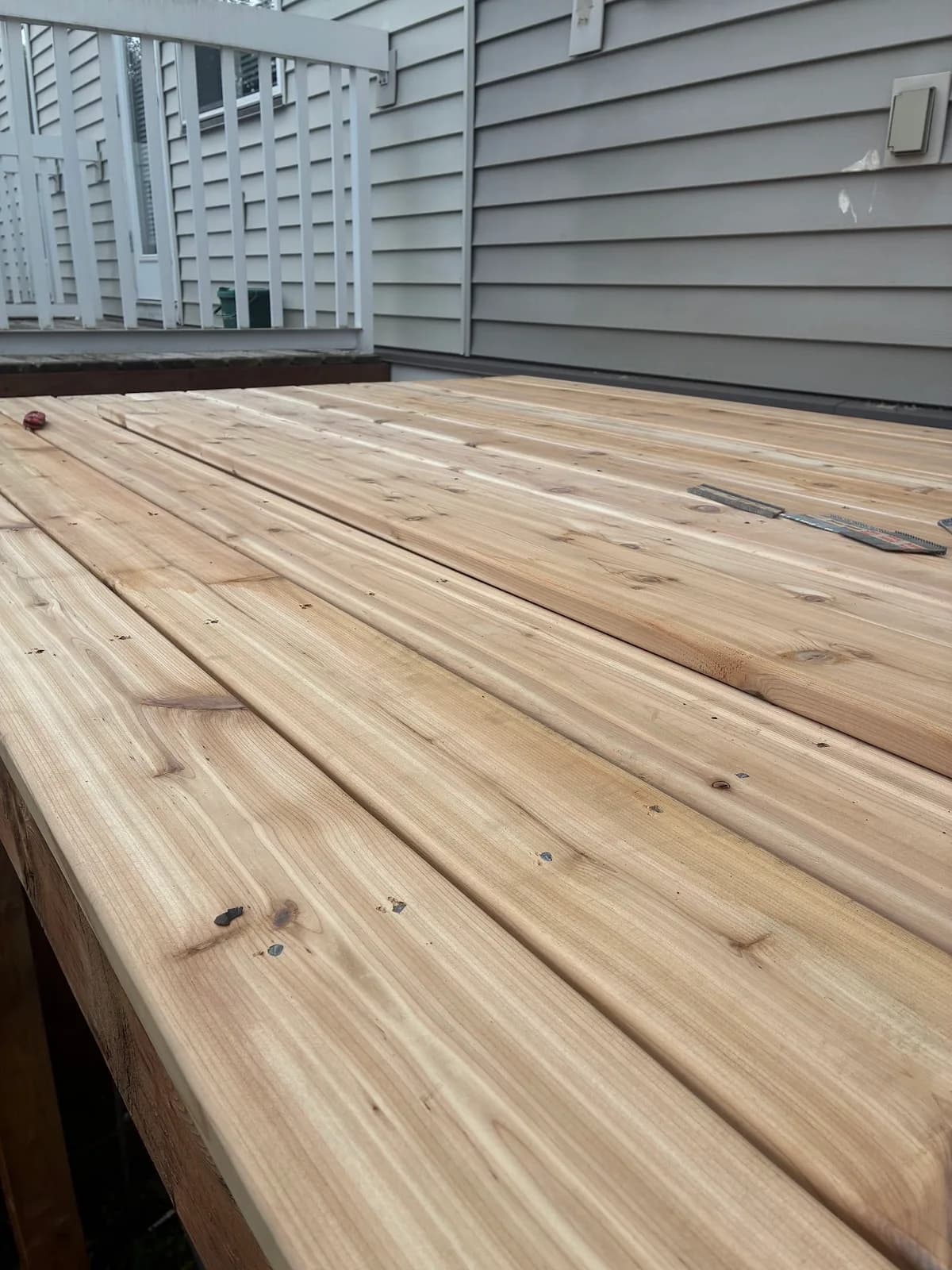 New wood deck boards extending along grey house siding toward a railing