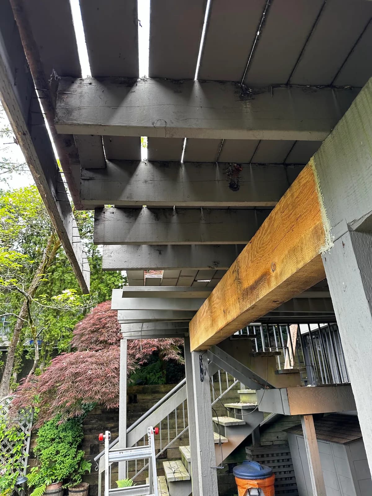 View beneath a raised deck showing painted joists and an exposed timber beam