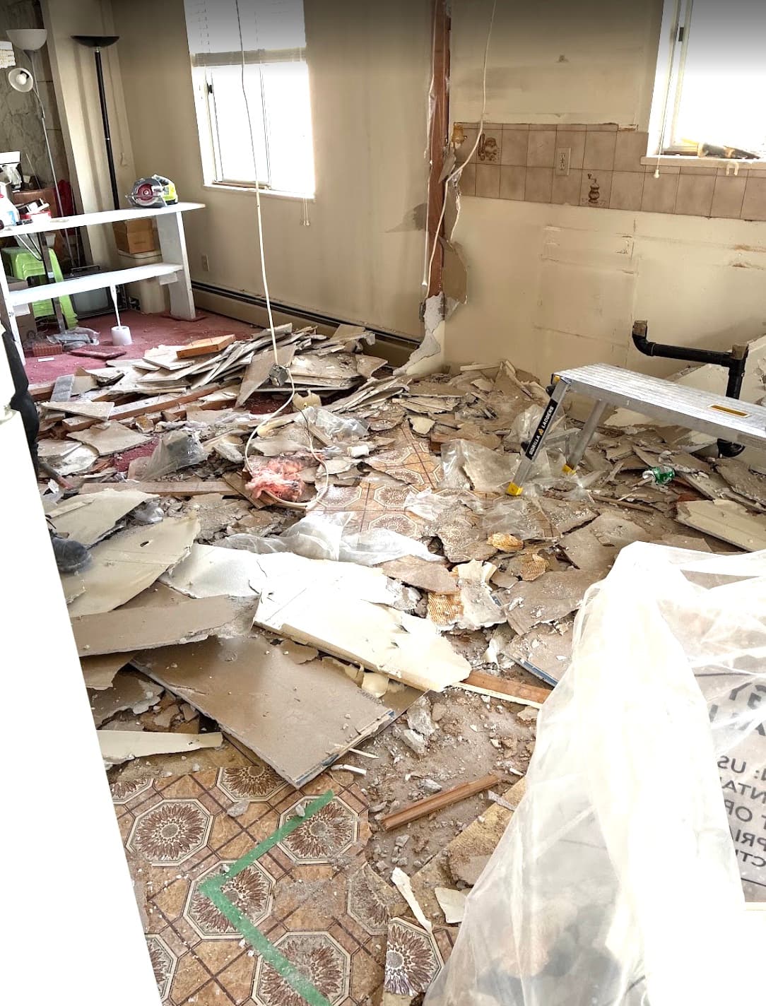 Interior demolition in progress with drywall and tile debris across the floor