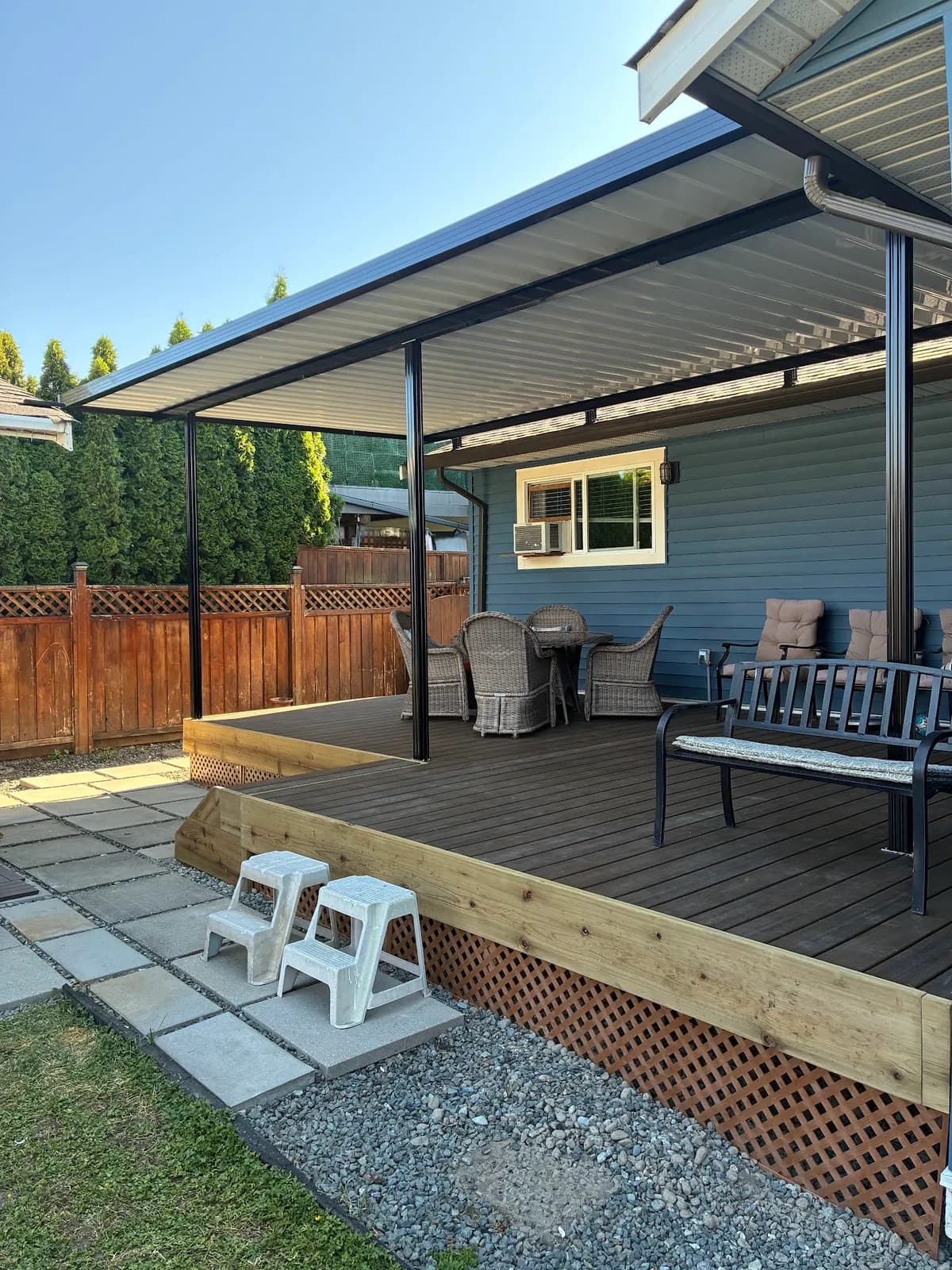 Deck surface and perimeter trim beneath a cover supported by black posts