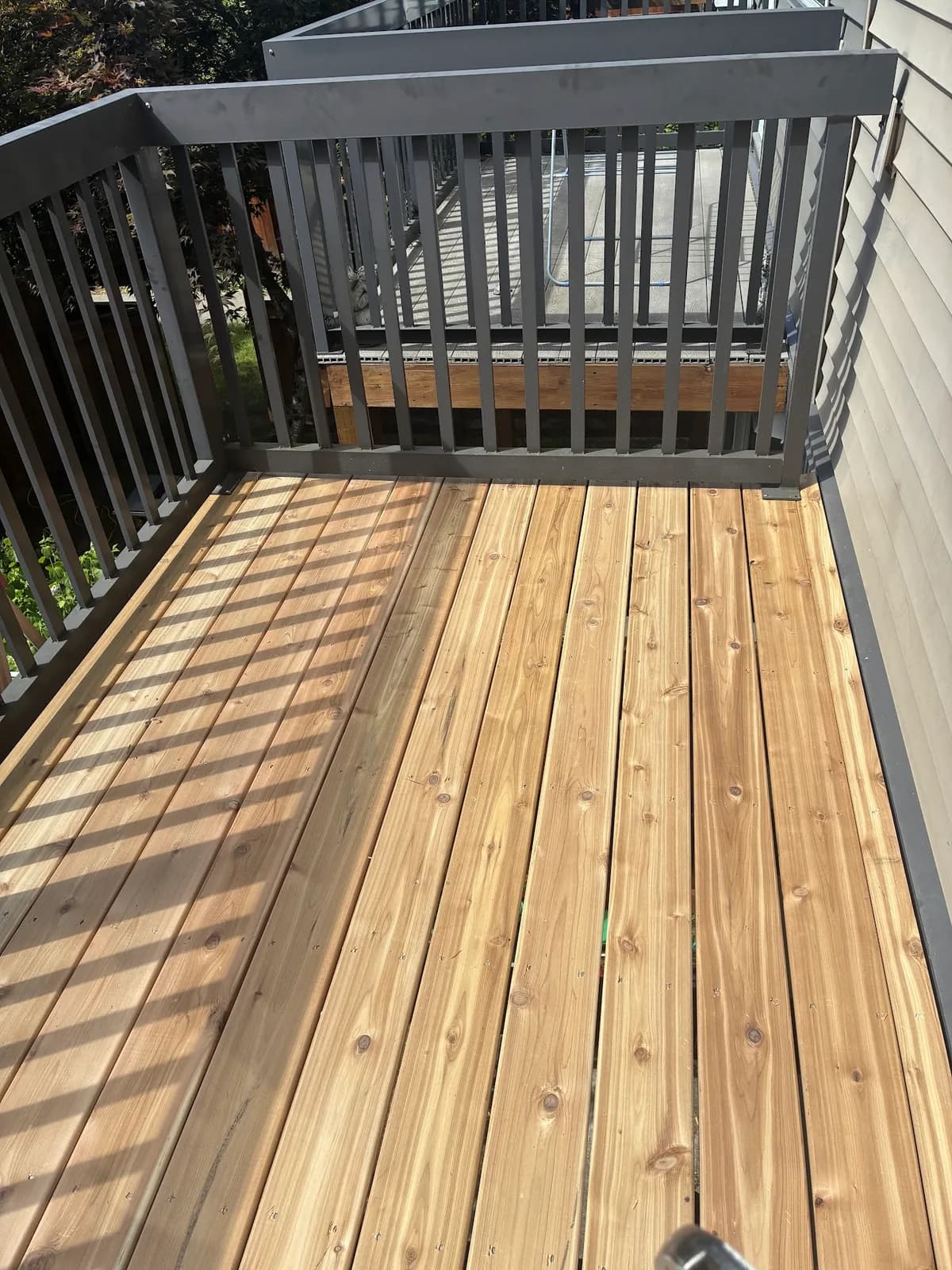Wood deck boards enclosed by grey railings beside a house